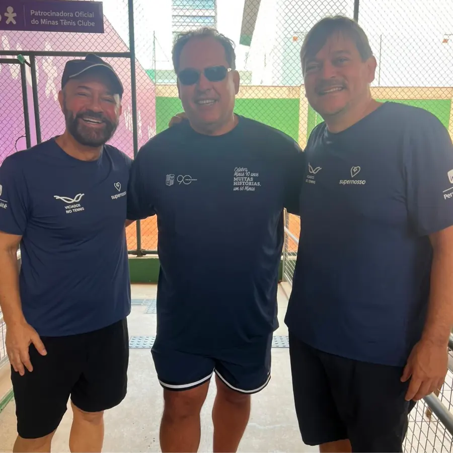 Três tenistas uniformizados posando na quadra