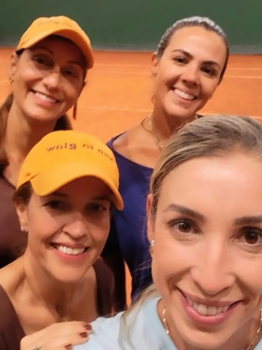 Quatro tenistas de viseira sorrindo na quadra